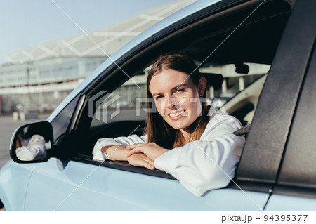 Portrait of a successful woman driving a car, smiling rejoicing and looking at the camera Portrait of a successful woman driving a car, smiling rejoicing and looking at the camera 94395377