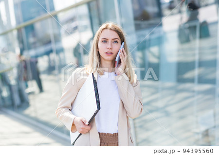 Young beautiful woman talking on a cell phone near the office, a businesswoman on a lunch break 94395560