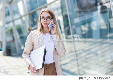 Young beautiful woman talking on a cell phone near the office, a businesswoman on a lunch break 94395562