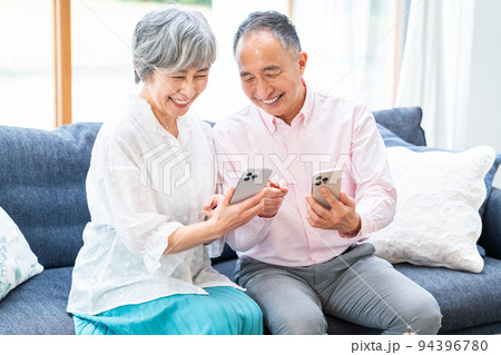 リビングでスマホを見るシニア夫婦 94396780