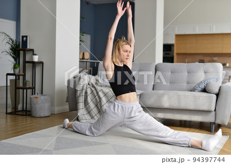 Woman working up forward splits warming up her legs. Woman working up forward splits warming up her legs. 94397744