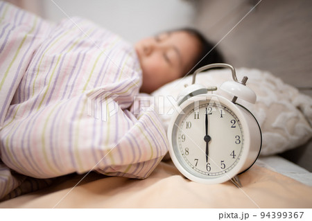 眠る子供と枕もとの目覚まし時計 眠る子供と枕もとの目覚まし時計 94399367
