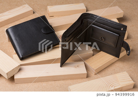 Two leather men's wallets on a textured wooden background, one wallet is open, the other is closed Two leather men's wallets on a textured wooden background, one wallet is open, the other is closed 94399916