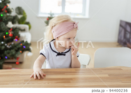Child girl with cochlear implants having fun at home with christmas tree background - hearing aid and innovative technologies for treatment of deafness 94400236