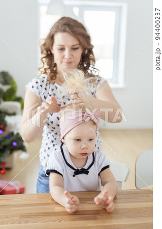 Mother doing hair for daughter with cochlear implant hearing aid - diversity concept. Innovative medical technologies 94400237
