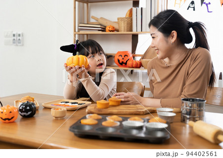 Mother and her daughter having fun at home. Happy Family preparing for Halloween. Mum and child cooking festive fare in the kitchen. 94402561