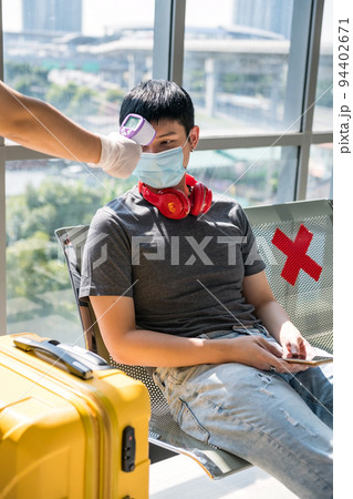 Airport officer check temperature of young Asian man in terminal Airport officer check temperature of young Asian man in terminal 94402671