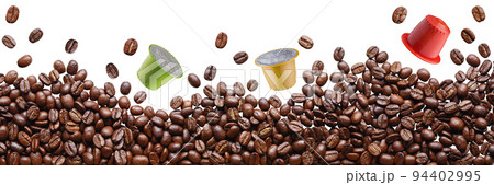 A pile of brown coffee beans lies and levitates, three capsules for a capsule coffee machine levitate between them, concept 94402995