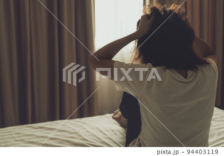 World Mental Health Day concept. Rear view of angry woman put hand on head and pulling hair. Mental illness woman sit on bed in bedroom. Woman with mental health problems. Stressed and nervous person. World Mental Health Day concept. Rear view of angry woman put hand on head and pulling hair. Mental illness woman sit on bed in bedroom. Woman with mental health problems. Stressed and nervous person. 94403119