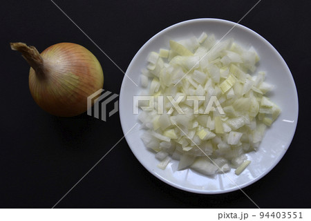 Sliced onion on a plate and onion on a black background. Onions on a black background and on a plate. Sliced onion on a plate and onion on a black background. Onions on a black background and on a plate. 94403551