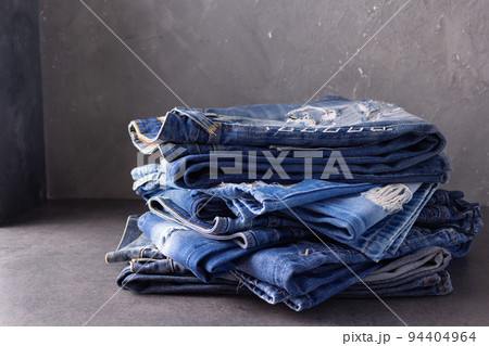 Blue jeans denim heap on table background. Jeans fabric stack as material surface Blue jeans denim heap on table background. Jeans fabric stack as material surface 94404964