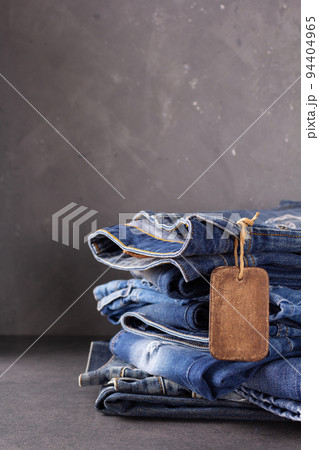 Blue jeans denim heap on table background. Jeans fabric material and tag price label 94404965