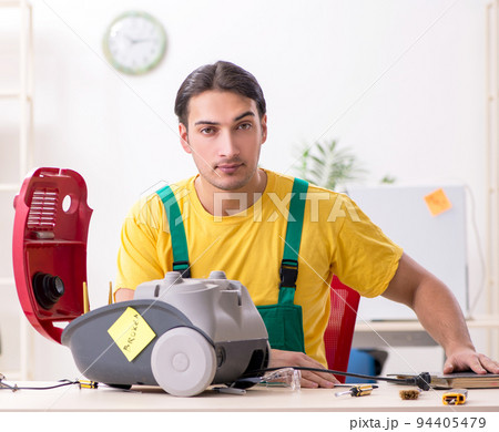 Man repairman repairing vacuum cleaner Man repairman repairing vacuum cleaner 94405479