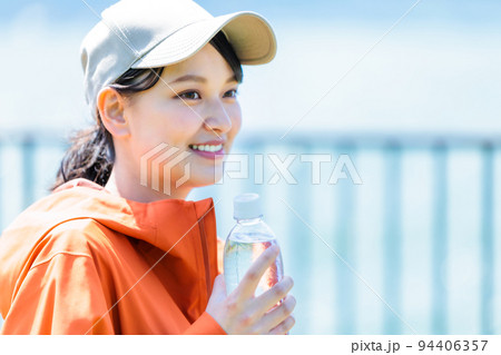 水分補給用のペットボトルを持つ若い女性 94406357