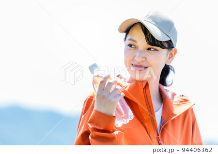 水分補給用のペットボトルを持つ若い女性 94406362