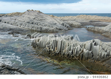 coastal cliffs formed by columnar basalt at low tide 94406862