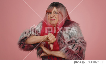 Upset woman in pink coat showing thumbs down sign gesture, disapproval, dissatisfied dislike Upset woman in pink coat showing thumbs down sign gesture, disapproval, dissatisfied dislike 94407592