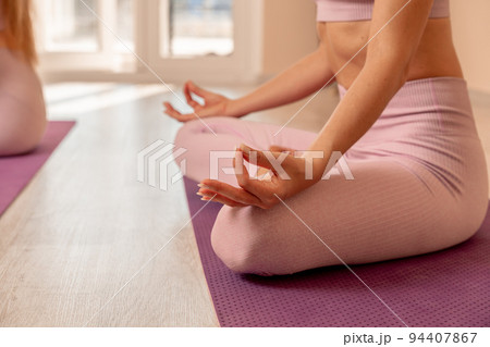 Middle aged woman looks good, practicing yoga, fitness, sports, training, woman doing exercises. She is wearing a pink top and leggings. The concept of grace and beauty of the body Middle aged woman looks good, practicing yoga, fitness, sports, training, woman doing exercises. She is wearing a pink top and leggings. The concept of grace and beauty of the body 94407867