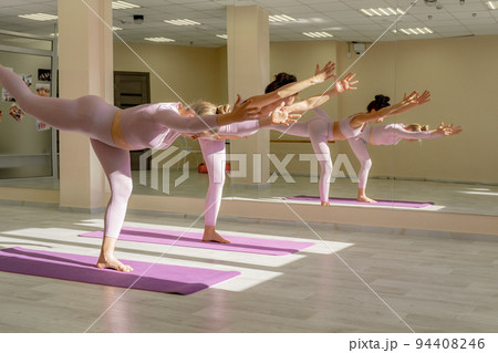 Two beautiful women cook doing yoga, sports together in the gym. Dressed in pink suits. The concept of grace and beauty of the body. Two beautiful women cook doing yoga, sports together in the gym. Dressed in pink suits. The concept of grace and beauty of the body. 94408246