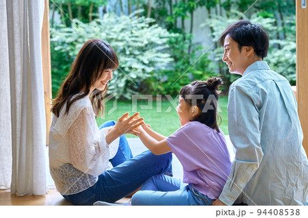 床に座ってリビングで団らんする笑顔の家族 94408538