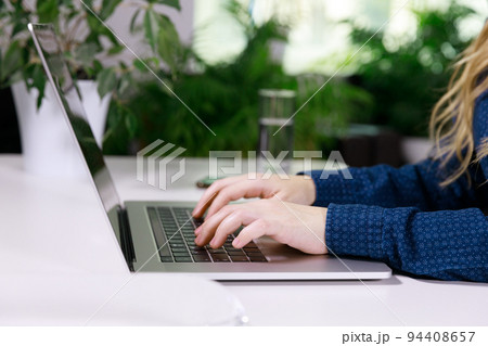 the hands of an invisible girl in a blue blouse are typing on a laptop the hands of an invisible girl in a blue blouse are typing on a laptop 94408657