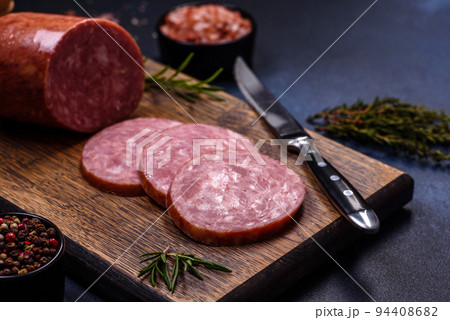 Delicious fresh smoked sausage cut with slices on a wooden cutting board 94408682
