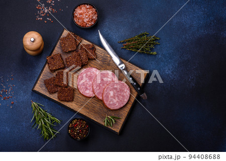 Delicious fresh smoked sausage cut with slices on a wooden cutting board Delicious fresh smoked sausage cut with slices on a wooden cutting board 94408688