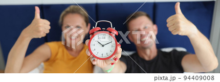 Married couple is holding alarm clock and thumbs up gesture 94409008