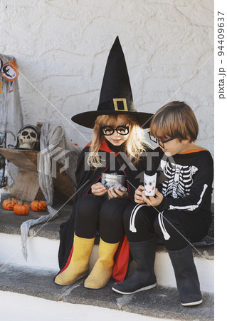 Kids in Halloween costumes are sitting on the porch 94409637