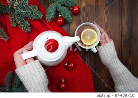 Women's hands pour tea from a teapot into a cup 94409710