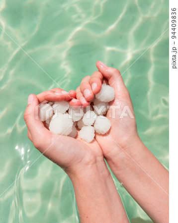 Hands holding sea salt crystals heart-saped on sea water background 94409836