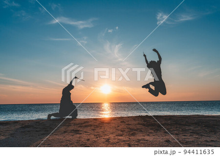日本海の夕暮れでシルエット遊びをする男女 日本海の夕暮れでシルエット遊びをする男女 94411635
