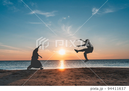 日本海の夕暮れでシルエット遊びをする男女 日本海の夕暮れでシルエット遊びをする男女 94411637