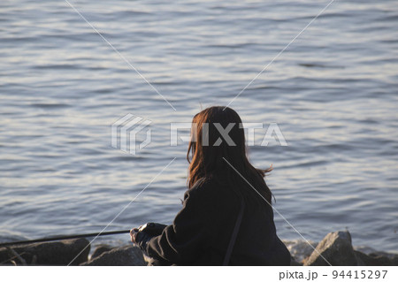 夕暮れの千葉の海岸に座っている女性の後ろ姿 94415297