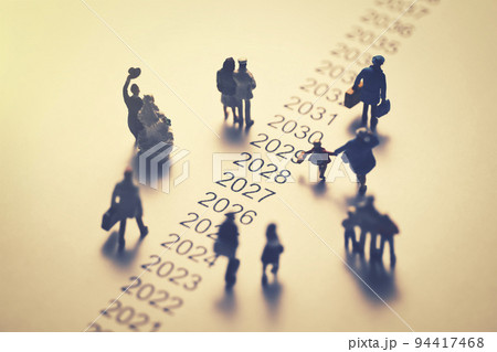 年表の横を歩くミニチュアの人々 94417468