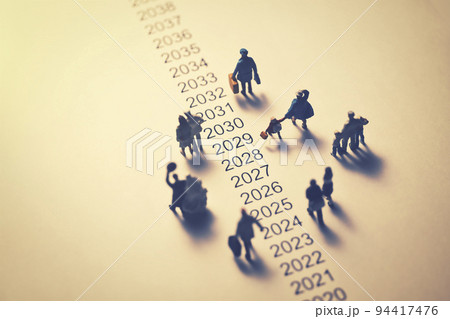 年表の横を歩くミニチュアの人々 94417476