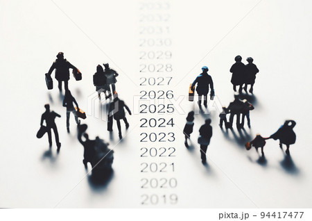 年表の横を歩くミニチュアの人々 94417477