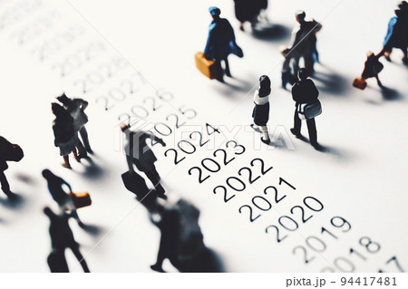 年表の横を歩くミニチュアの人々 94417481