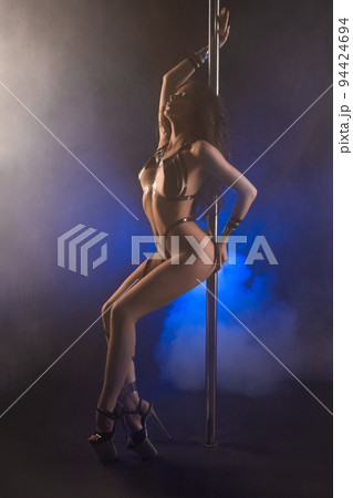 Sensual young woman in tape bodyart dancing near pole in studio 94424694