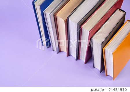 Stack of colorful books on purple background Stack of colorful books on purple background 94424950