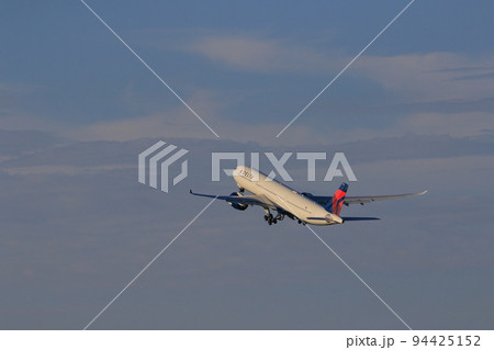 夕日を浴びて離陸する旅客機　 94425152