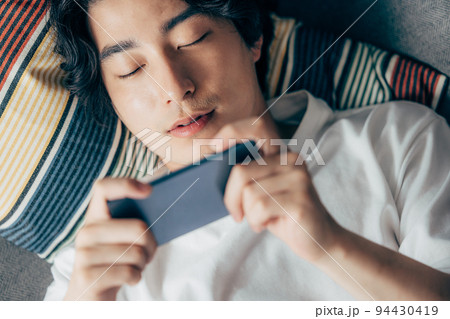 ソファでスマホを使う若い男性 ソファでスマホを使う若い男性 94430419