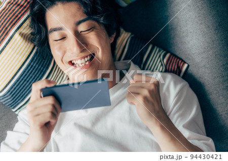 ソファでスマホを使う若い男性 ソファでスマホを使う若い男性 94430421