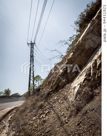 Dry asphalt empty automobile road with electric pole near rocks on a sunny summer day. Car travel trip concept background. Stories vertical format. Vintage and faded matt style in tinted photo Dry asphalt empty automobile road with electric pole near rocks on a sunny summer day. Car travel trip concept background. Stories vertical format. Vintage and faded matt style in tinted photo 94431923