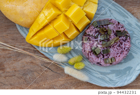 Close-up of Fresh ripe yellow mango fruit (Barracuda mango) and Riceberry topping pandan leaf. Close-up of Fresh ripe yellow mango fruit (Barracuda mango) and Riceberry topping pandan leaf. 94432231