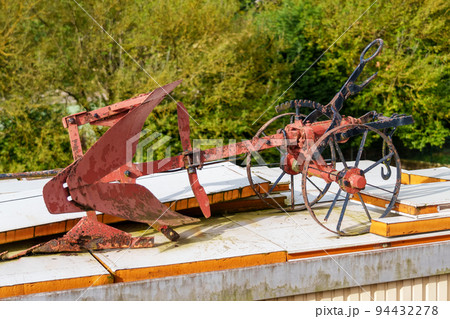 Vintage metal plow with wheels for tillage. Antique agricultural equipment for plowing the soil. Close up Vintage metal plow with wheels for tillage. Antique agricultural equipment for plowing the soil. Close up 94432278