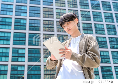 タブレットを持ったオフィスカジュアルの若いビジネスマン タブレットを持ったオフィスカジュアルの若いビジネスマン 94433401