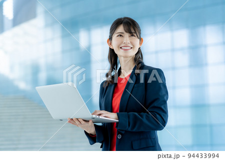 オフィスのロビーでノートパソコンを手に操作する若いビジネスウーマン 94433994