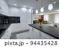 Large black and white expensive well-designed modern kitchen in studio interior, black marble countertop 94435428