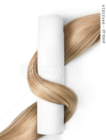 A strand of blond hair with a bottle of shampoo on a white background. Close-up. 94435814